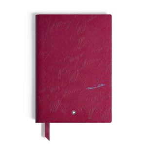 Maroon patterned notebook with a blue signature, ribbon bookmark, and a small round emblem.