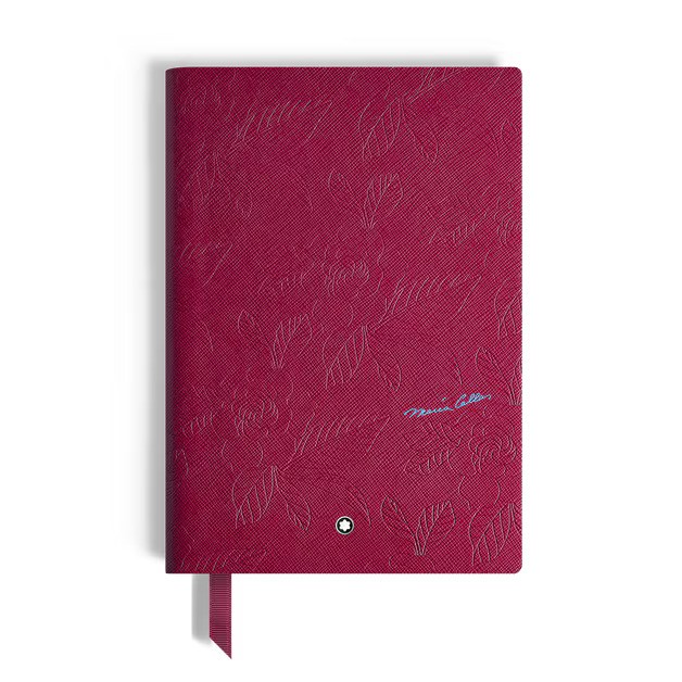 Maroon patterned notebook with a blue signature, ribbon bookmark, and a small round emblem.
