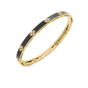 Gold bracelet with black enamel inlays and diamond-studded flower accents, viewed from the side in a jewelry photo